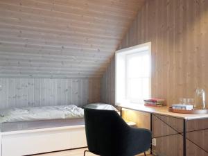 a bedroom with a bed and a chair and a window at Holiday home Averøy VII in Karvåg