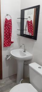 a bathroom with a sink and a toilet and a mirror at Quartos Residencial Arcos in Arcos