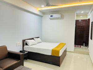 1 dormitorio con 1 cama y 1 silla en Hotel Pleasure, en Surat