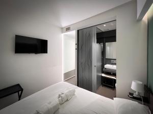 a white bedroom with a bed and a television at Mutina Suites in Modena