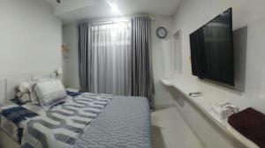 a bedroom with a bed and a flat screen tv at Astara Hotel Balikpapan in Balikpapan