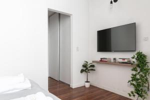 sypialnia z telewizorem z płaskim ekranem na białej ścianie w obiekcie Fliphaus Humahuaca 4000 - 3 Bd In Almagro w BuenosAires