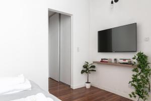 1 dormitorio con TV de pantalla plana en una pared blanca en Fliphaus Humahuaca 4000 - 3 Bd In Almagro en Buenos Aires