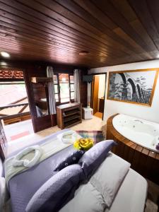 a bedroom with a tub and a bed with pillows at Canoa Abraão in Abraão