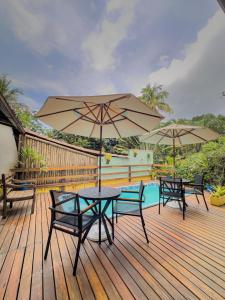 una terraza con mesas, sombrillas y una piscina en Canoa Abraão en Ilha Grande