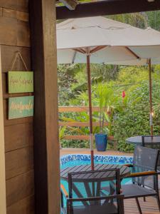 a table and chairs with an umbrella next to a pool at Canoa Abraão in Abraão