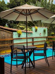 a table and chairs with an umbrella next to a pool at Canoa Abraão in Abraão