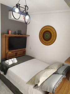 1 dormitorio con 1 cama blanca y TV en la pared en Studio Aconchegante no Coração de SP metrô próximo, en São Paulo