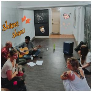 Un gruppo di persone sedute in una stanza che suonano la chitarra di Funky Buddha Hostel a Mysore