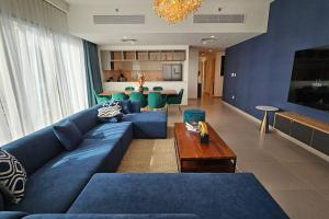 杜拜的住宿－Luxury 3 Bed + Maid Room in Downtown Apt With Burj Khalifa View，客厅配有蓝色的沙发和桌子