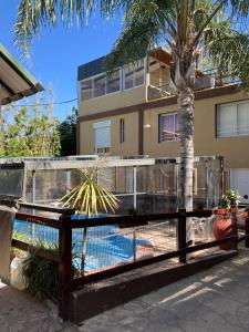 a fence with a palm tree in front of a building at Carlos Paz Departamentos in Villa Carlos Paz