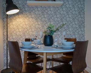 uma mesa com cadeiras e um vaso com uma planta em GuestReady - Homely Leeds City Apartment Sleep 4 em Meanwood