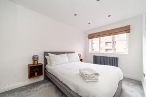 een slaapkamer met een bed met witte lakens en een raam bij Home from Home in Londen