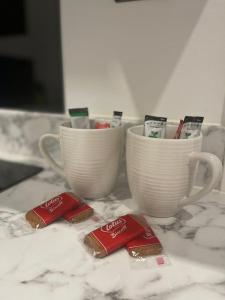 two cups on a counter with two packets of toothpaste at Luxury Duplex City Centre Apartment in Leeds