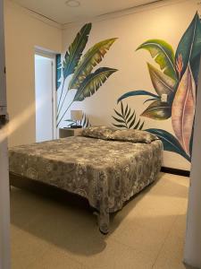 a bedroom with a bed with a mural on the wall at Baku Laureles Hostel in Medellín