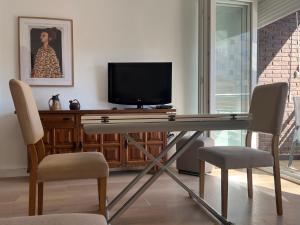 a desk with a television and two chairs in a room at Piso y parking Zapillo playa in Almería