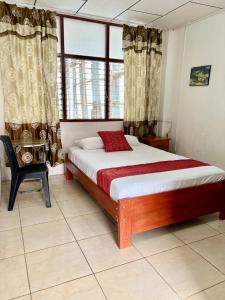 1 dormitorio con 1 cama, 1 silla y 1 ventana en Hospedaje Casa Amazónica Iquitos en Iquitos