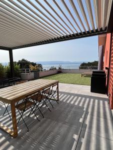 a wooden table on a patio with a view of the ocean at IMMODREAMS - L'Attik with lake views and 80m2 terrace in Évian-les-Bains