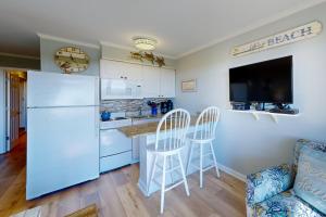 a kitchen with a white refrigerator and a bar with stools at Sea Side Villas 171 in Hilton Head Island