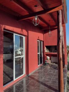 ein rotes Haus mit einer großen Glasschiebetür in der Unterkunft Cabaña Carlos Paz in Villa San Nicolás