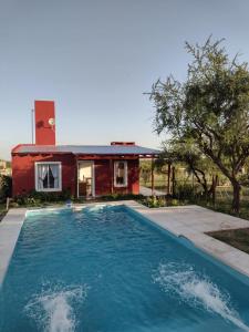 a house with a swimming pool in front of a house at Cabaña Carlos Paz in Villa San Nicolás