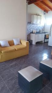 a living room with a yellow couch and a kitchen at Cabaña Carlos Paz in Villa San Nicolás