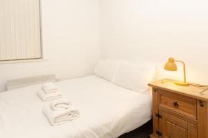 - une chambre avec un lit blanc et des serviettes dans l'établissement Cosy 2BR Apartment in Nottingham, à Nottingham