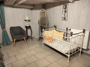 a bedroom with a crib and a chair and a table at Appartement dans le Morvan 16 min de l'autoroute in Beauvilliers