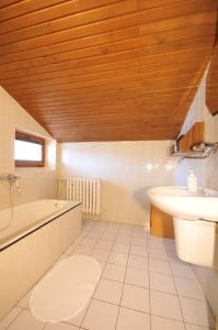 a bathroom with a wooden ceiling and a tub and a sink at Penzion Helena in Stará Lesná