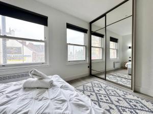 a bedroom with a white bed and large windows at Cute, Stylish 1 Bedroom Leeds City Apartment in Leeds