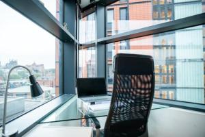 a glass desk with a laptop and a chair in a room at Modern 2-Bed Flat with Breathtaking City Views in Leeds