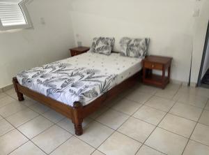 Bett in einem Zimmer mit zwei Nachttischen und einem sidx sidx sidx in der Unterkunft Résidence Lilas Rose in Andilana