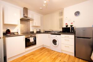 - une cuisine avec des placards blancs et un lave-linge/sèche-linge dans l'établissement Cosy 2BR Apartment in Nottingham, à Nottingham