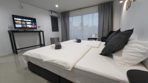 a bedroom with a large white bed with a flat screen tv at Chu-Cha's Rooms in Koh Samui