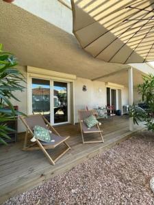 due sedie sedute su una terrazza di legno di fronte a una casa di Appartement à Cala Rossa a Lecci