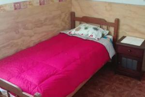 1 cama con manta roja y mesita de noche en Cabaña a metros de la playa San Ignacio, Niebla, en Valdivia