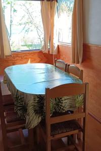 mesa de comedor con 2 sillas y mesa azul en Cabaña a metros de la playa San Ignacio, Niebla, en Valdivia