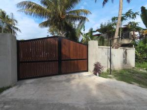 a wooden gate in a driveway with palm trees at Shine Breeze villa in Weligama