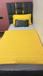 a bed with a yellow comforter and a pillow at Oujda hay Salam doha in Oujda