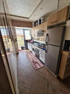 a kitchen with a stainless steel refrigerator and wooden floors at Oujda hay Salam doha in Oujda