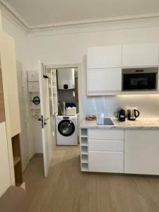 a kitchen with white cabinets and a washing machine at Appartement Vincennes cozy in Vincennes