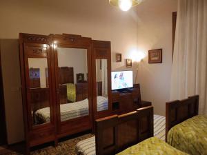 1 Schlafzimmer mit 2 Betten, einem Spiegel und einem TV in der Unterkunft Villa Elda - b&b in historic house in Montecatini Terme