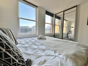 a bedroom with a large white bed with large windows at Sleek Stylish 1 Bedroom Leeds City Apartment in Leeds