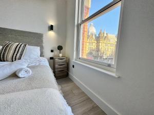 een slaapkamer met een bed en een groot raam bij Sleek Stylish 1 Bedroom Leeds City Apartment in Leeds