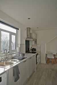 uma cozinha branca com um lavatório e uma janela em GuestReady - Comfortable Leeds City Apartment em Kirkstall