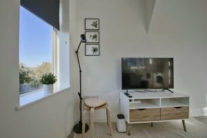 uma sala de estar com uma televisão e uma cadeira em GuestReady - Comfortable Leeds City Apartment em Kirkstall