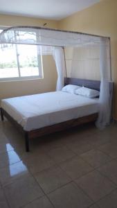 uma cama de dossel num quarto com uma janela em Nyali cozy home em Mombasa