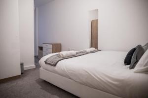 - une chambre avec un grand lit blanc et une commode dans l'établissement GuestReady - City Centre Apartment, Sleep 4, à Hunslet