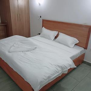 ein großes Bett mit weißer Bettwäsche und Kissen in der Unterkunft Jade luxury apartments Diani in Mombasa
