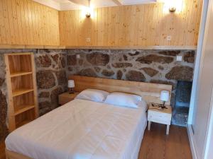 - une chambre avec un lit et un mur en pierre dans l'établissement Casa Pinhão de Sousa, à Vieira do Minho